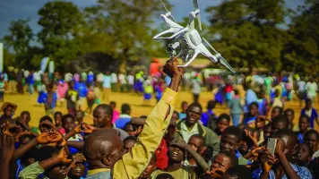 Residents of Kasungu, in central Malawi, gather during a demonstration of unmanned aerial vehicle (drone) technology. The Government of Malawi and UNICEF are testing the use of drones for humanitarian purposes. 28 June 2017. © UNICEF/UN070228/Chisiza