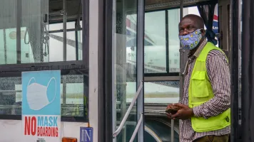 Airport staff member at the Lagos Airport stands at the door of a bus as domestic flights resume in Nigeria, Credit: Oluwafemi Dawodu / Shutterstock