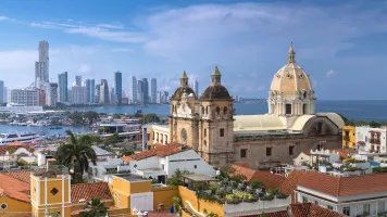 Colonial church in the foreground of an image of a city with high-rise buildings in the background.