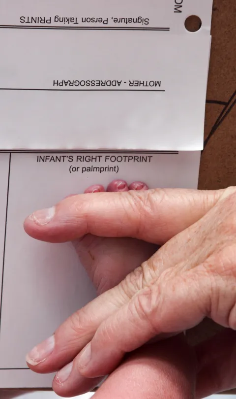 Doctor recording a newborns foot prints on the birth certificate.