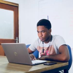 Person sitting at a laptop on a desk. Photo by Desola Lanre-Ologun, via Unsplash