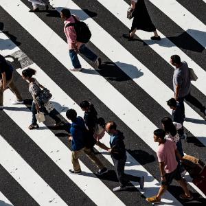 An overhead view of people walking across a busy road crossing. Photo by Ryoji Iwata, via Unsplash