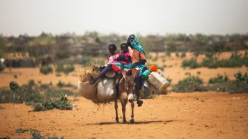 A woman with her children rides a donkey around a new settlement in Zam Zam camp for Internally Displaced People (IDP), North Darfur.