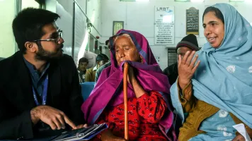 Naushad Bibi and her daughter-in-law talking to Muhammad Suleman (a data collector) at an eye hospital in Mandra, Pakistan. @Sightsavers/Jamshyd Masud.