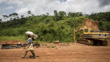 Man walking across a mining site in Ghana