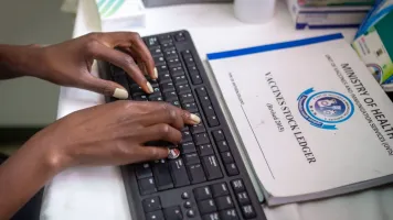 An attendant enters vaccination data on a computer at a clinic in Nairobi, Kenya.