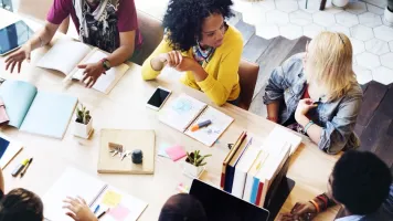 Group of people sitting around a table talking in an office setting.