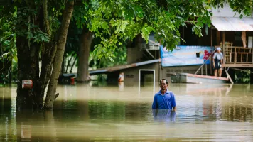 A man in Thailand standing in the middle of a flooded street