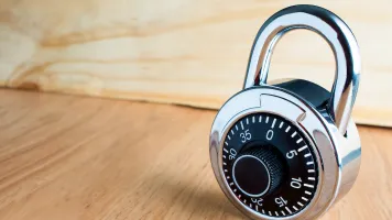 A padlock resting on a wooden shelf.