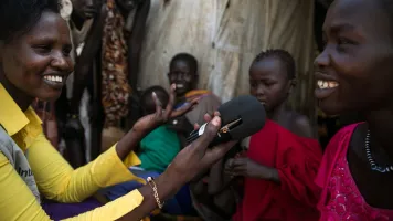 Julia Diew of Internew’s Boda Boda Talk project interviews Sunday James about the support she provides to her family in the United Nations Protection of Civilians Camp. Credit: Internews via USAID.