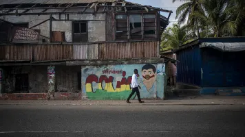 Person in Accra, Ghana walking in front of wall of graffiti that says "stay home - COVID." Credit: Jordi Perdigo/Global Partnership for sustainable development data