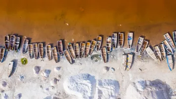 An aerial view of colorful boats lined up along a shoreline.