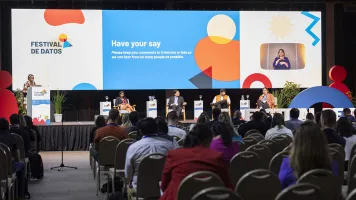 Five speakers on the stage in front of the audience for the AI town hall debate at Festival de Datos. A colourful slide in the background says: 'Have your say'. Photo by Nicolás Donatte