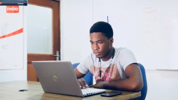 Person sitting at a laptop on a desk. Photo by Desola Lanre-Ologun, via Unsplash 