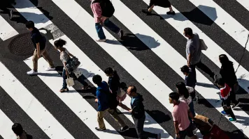 An overhead view of people walking across a busy road crossing. Photo by Ryoji Iwata, via Unsplash