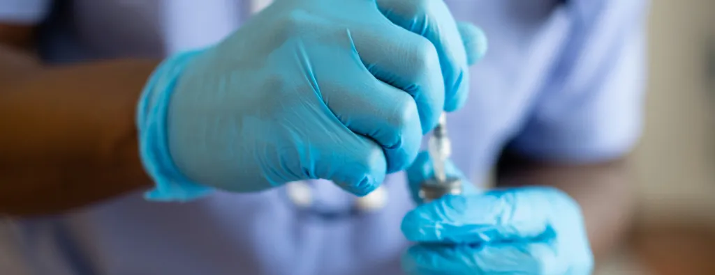 Doctor with gloves and a syringe. Unsplash / Nappy