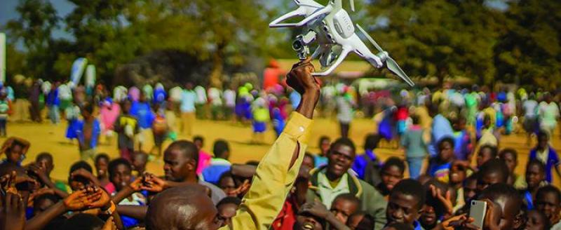 Residents of Kasungu, in central Malawi, gather during a demonstration of unmanned aerial vehicle (drone) technology. The Government of Malawi and UNICEF are testing the use of drones for humanitarian purposes. 28 June 2017. © UNICEF/UN070228/Chisiza