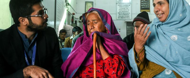 Naushad Bibi and her daughter-in-law talking to Muhammad Suleman (a data collector) at an eye hospital in Mandra, Pakistan. @Sightsavers/Jamshyd Masud.