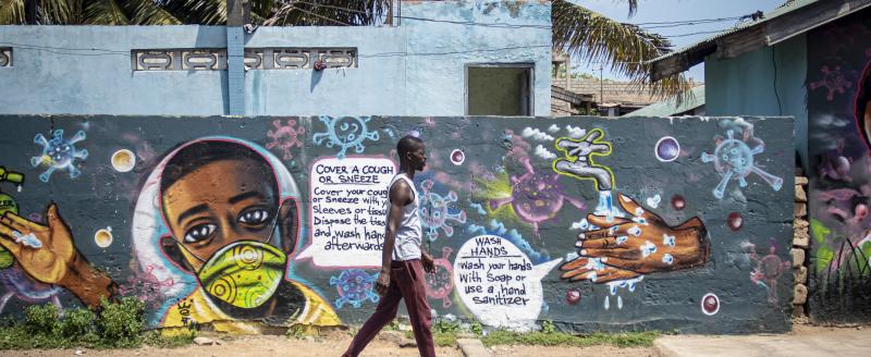 Man walking in front of a wall with COVID-19 graffiti