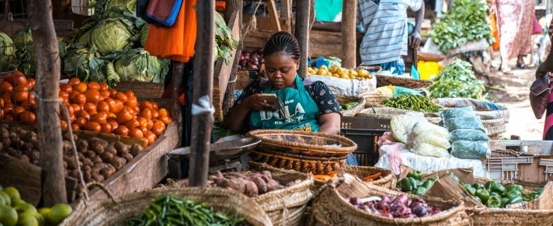 Seller in a Kenyan food market on her phone