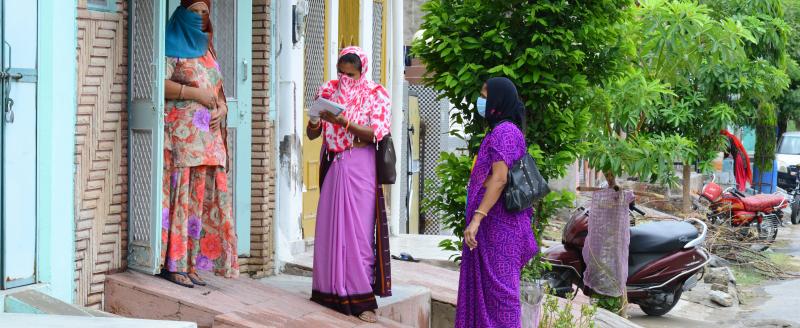 Anganwadi workers wearing mask interacts with a woman during a door-to-door survey to check the spread of novel coronavirus, on the outskirts of Beawar.