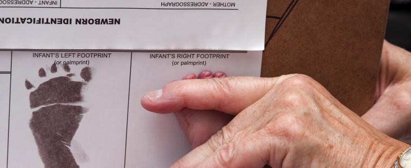 Doctor recording a newborns foot prints on the birth certificate.