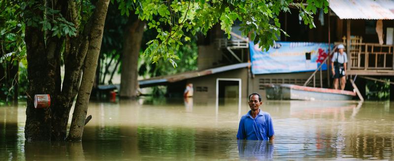 A man in Thailand standing in the middle of a flooded street