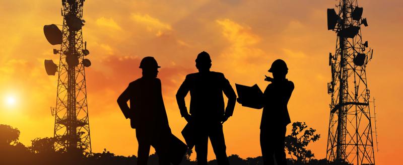 Silhouette of mobile network engineers at sunset.