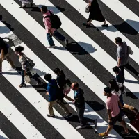An overhead view of people walking across a busy road crossing. Photo by Ryoji Iwata, via Unsplash
