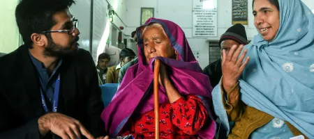 Naushad Bibi and her daughter-in-law talking to Muhammad Suleman (a data collector) at an eye hospital in Mandra, Pakistan. @Sightsavers/Jamshyd Masud.
