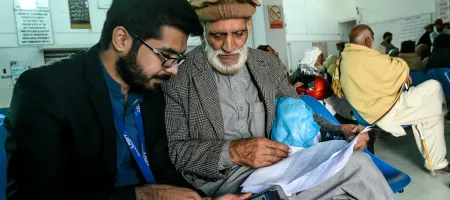 Two men sitting in a waiting room looking at a tablet