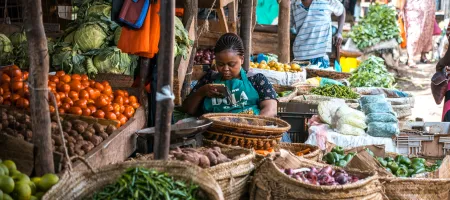 Seller in a Kenyan food market on her phone 