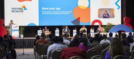 Five speakers on the stage in front of the audience for the AI town hall debate at Festival de Datos. A colourful slide in the background says: 'Have your say'. Photo by Nicolás Donatte