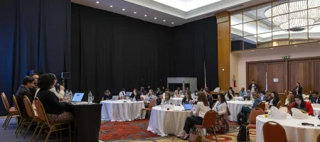 Attendees sit at six round tables in front of a panel of four speakers at the workshop to discuss progress on the Power of Data High Impact Initiative, at Day Zero of Festival de Datos