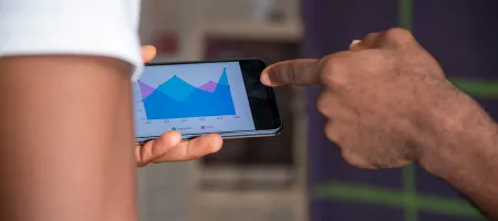 Two people viewing graph on a mobile phone - via Shutterstock