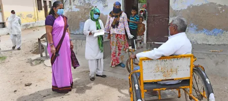 Beawar, India-April 20,2020: Anganwadi workers wearing protective face mask interacts with a disabled man during a door-to-door survey