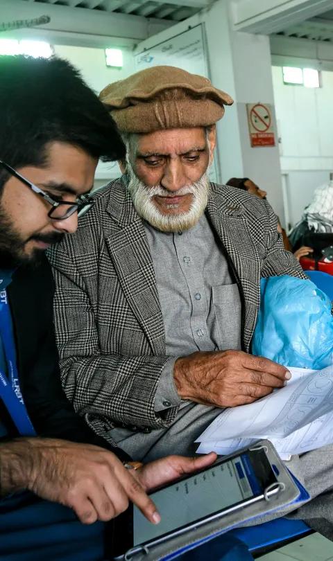 Two men sitting in a waiting room looking at a tablet