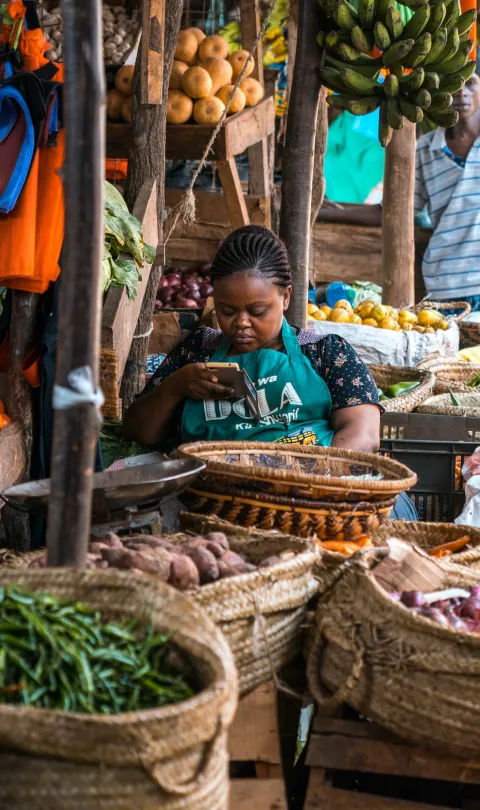 Seller in a Kenyan food market on her phone 
