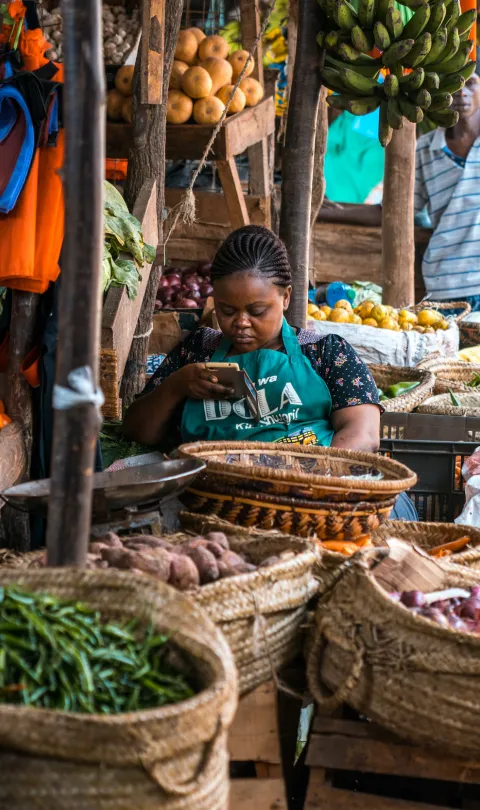 Seller in a Kenyan food market on her phone 