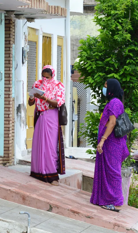 Anganwadi workers wearing mask interacts with a woman during a door-to-door survey to check the spread of novel coronavirus, on the outskirts of Beawar.