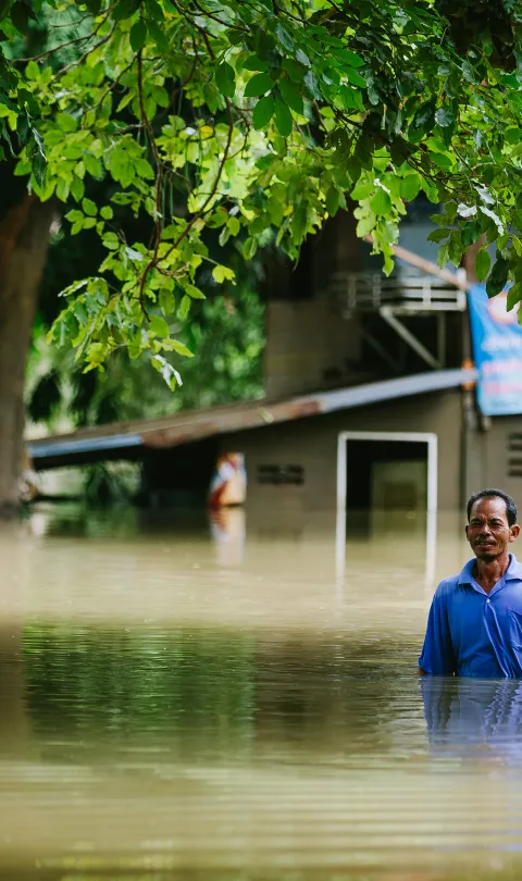 A man in Thailand standing in the middle of a flooded street