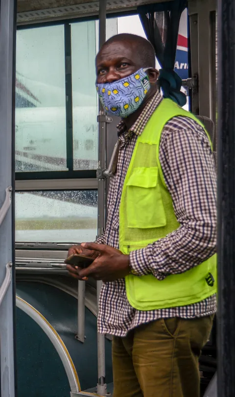 Airport staff member at the Lagos Airport stands at the door of a bus as domestic flights resume in Nigeria, Credit: Oluwafemi Dawodu / Shutterstock
