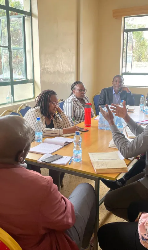 Participants in learning exchange from Ministries of Health in Kenya and Zanzibar sitting around a table holding debrief meeting