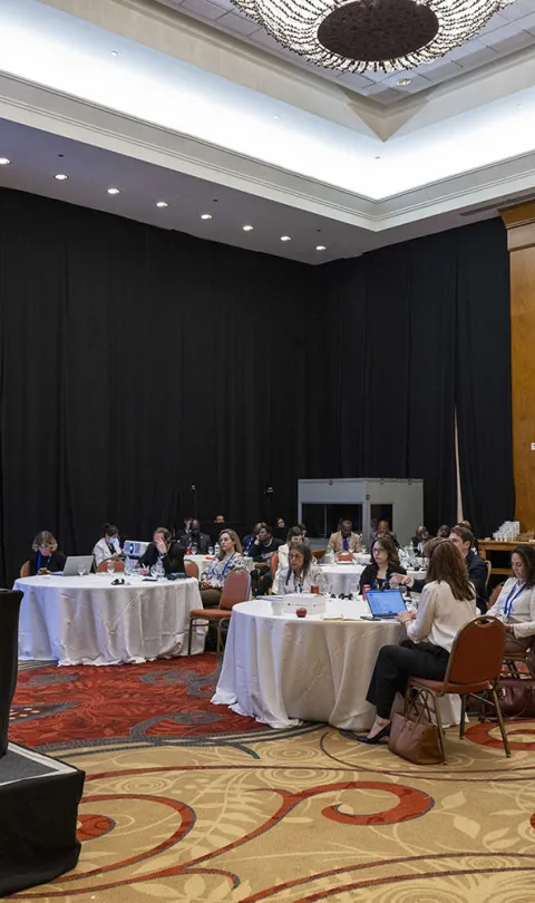 Attendees sit at six round tables in front of a panel of four speakers at the workshop to discuss progress on the Power of Data High Impact Initiative, at Day Zero of Festival de Datos