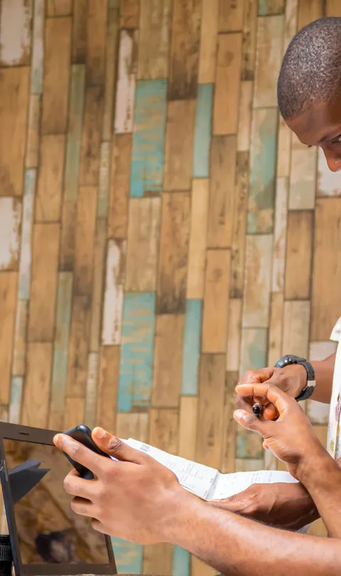 Two people collaborating, looking at two laptops and a smartphone