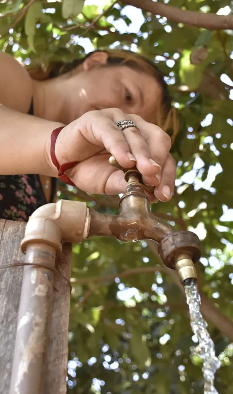 Woman collects water from tap in Peguaho Kokuere, Itá, Paraguay