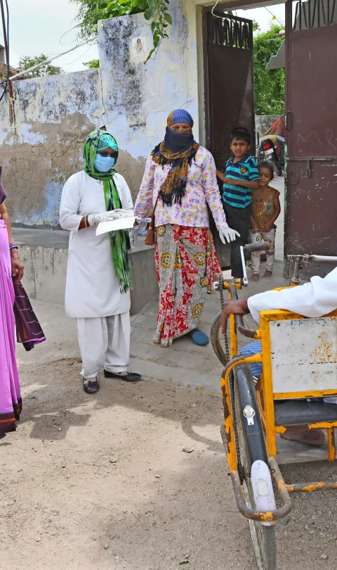 Beawar, India-April 20,2020: Anganwadi workers wearing protective face mask interacts with a disabled man during a door-to-door survey