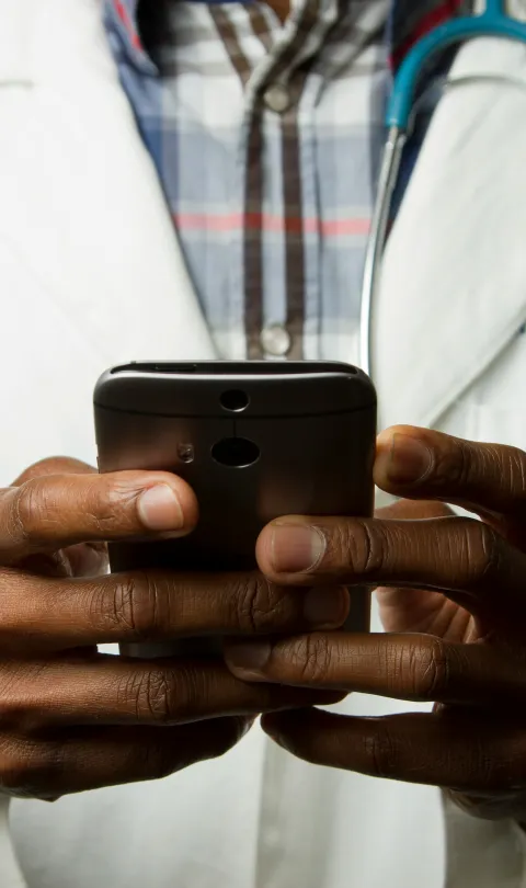 Doctor holding mobile phone. Photo: National Cancer Institute / Unsplash 