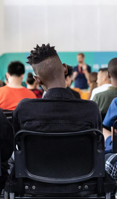 Three students in the back row of a class in school. Photo by Sam Bailey, via Unsplash