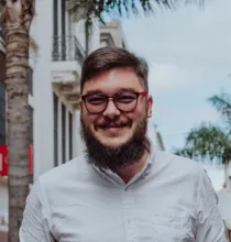 White man with beard and glasses smiling at the camera.
